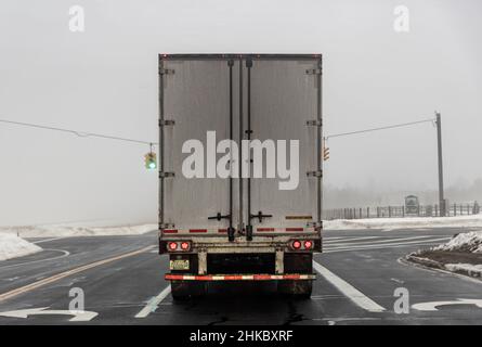 Vista posteriore di un semirimorchio su strada in una giornata invernale nebbia Foto Stock