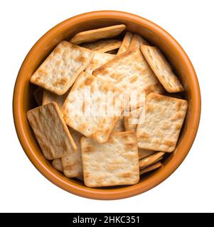 biscotti in una ciotola, croccanti cracker di forma quadrata, spuntino tempo del tè isolato su sfondo bianco, preso dall'alto Foto Stock