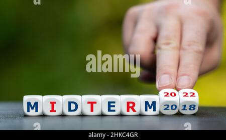 Simbolo per le elezioni di medio termine del 2022 negli Stati Uniti. La mano gira i dadi e cambia l'espressione 'midterm 2018' in 'midterm 2022'. Foto Stock