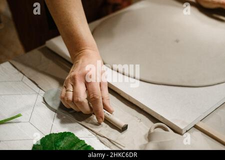 Le mani della donna lavorano con argilla sul tavolo Foto Stock