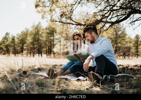 Felice giovane coppia sorridente e che legge nella natura Foto Stock