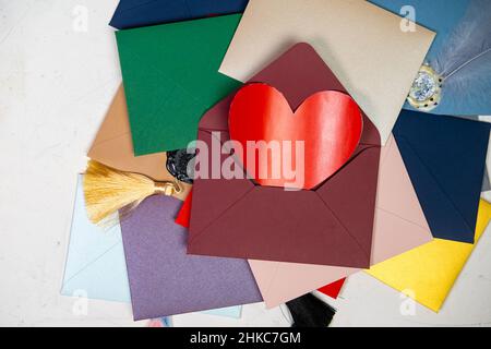 Cuore rosso in una busta. Un sacco di buste colorate. Buste sigillate con cera. Corrispondenza, concetto di giorno di San Valentino. Foto Stock