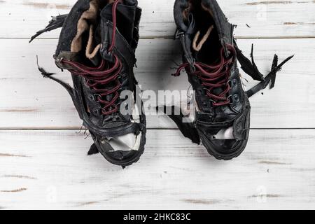 Stivali da scarpe logorati. Sfondo di legno chiaro. Scarpe strappate e rotte. Foto Stock