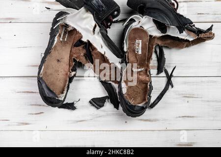 Stivali da scarpe logorati. Sfondo di legno chiaro. Scarpe strappate e rotte. Foto Stock