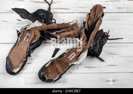 Stivali da scarpe logorati. Sfondo di legno chiaro. Scarpe strappate e rotte. Foto Stock