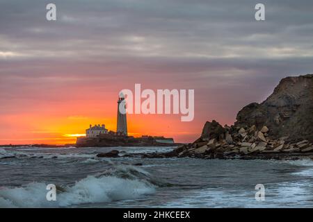 Un'alba spettacolare al faro di St Mary a Whitley Bay, mentre il cielo erutta di colore Foto Stock