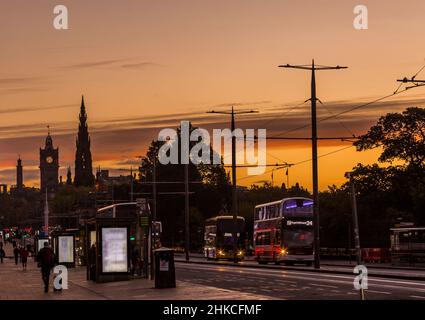 Princes Street a Edimburgo, Scozia, la tradizionale strada principale per lo shopping della città all'alba, con linee di tram e autobus in scena Foto Stock