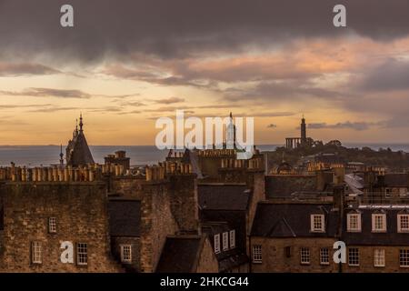 Guardando attraverso i tetti di Edimburgo mentre il sole tramonta in una giornata nuvolosa in Scozia Foto Stock