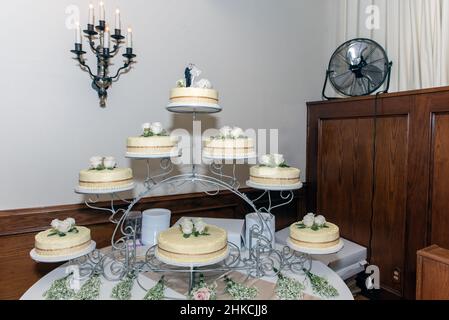Torta nuziale visualizzata su un arco di piani, quindi c'è molto dolce dessert per tutti a mangiare. Foto Stock