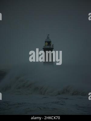 I venti della forza della balla da Storm Arwen causano le onde giganti per battere il faro e il molo nord che sorvegliano la bocca del Tyne a Tynemouth, Inghilterra Foto Stock