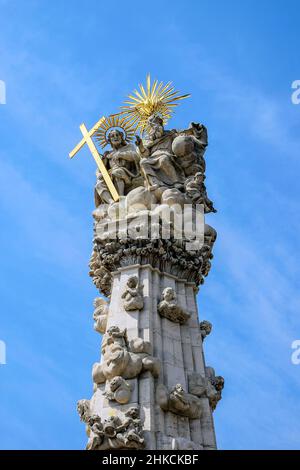 Frammento della colonna della Santissima Trinità (colonna peste) a Budapest contro il cielo blu con le nuvole. Colonna peste situata sulla collina del Castello nel mezzo di Trinity Sq Foto Stock