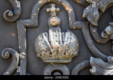 Frammento di una porta in metallo forgiato con ornamento a corona a croce. Colore nero. Design religioso. Il simbolo del potere. Primo piano. Messa a fuoco selettiva. Co Foto Stock