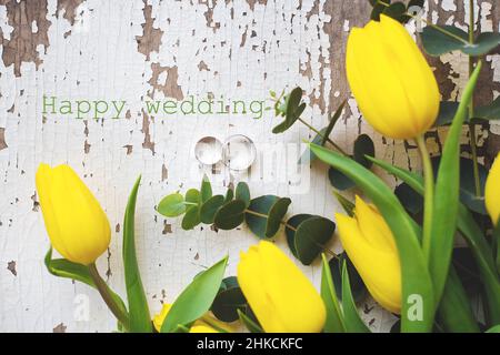 anelli di nozze con tulipani gialli, iscrizione felice matrimonio Foto Stock