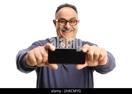 Uomo maturo sorridente che prende un selfie con uno smartphone isolato su sfondo bianco Foto Stock