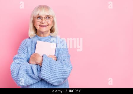Ritratto di attraente cheery creativo intelligente grigio-capelli donna abbracciante spazio copia libro isolato su sfondo rosa pastello colore Foto Stock
