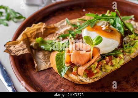 Bruschetta con avocado, salmone salato, microgrene e uova in camicia, Closeup Foto Stock