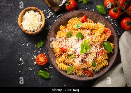 Pasta italiana alla arrabiata con basilico e parmigiano su tavola scura. Foto Stock