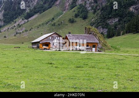 19.08.2021 Seealpsse Svizzera: Vecchio stile caseificio alpino costruito accanto ad un muro di roccia, lattine di latte vuoto di fronte alla casa, tedesco caseificio alpino segno wi Foto Stock