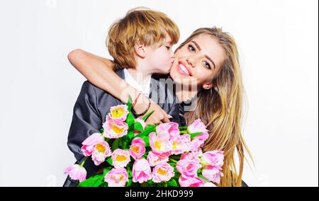 Figlio bacia felice madre e dà bouquet di tulipani congratulandosi con lei per la madre giorno o compleanno Foto Stock