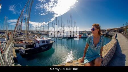 Attraente donna matura posa su una barca nel porto di Marina del sur a Tenerife 25 dicembre 2018 Foto Stock