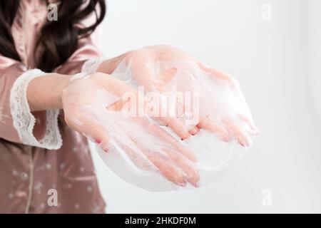 Trattamenti viso e bellezza. Foglio maschera idratante isolato su sfondo bianco. Foto Stock