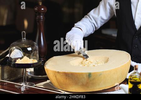 Il cameriere taglia pezzi di parmigiano Foto Stock