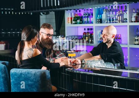 Il barman versa cocktail a una giovane coppia in un ristorante Foto Stock