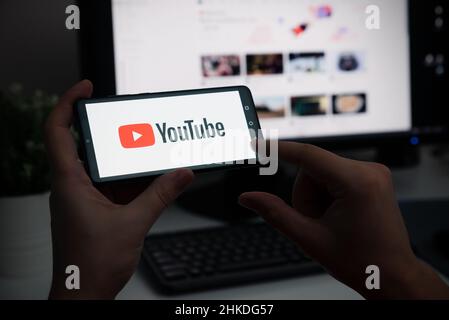 Wroclaw, Polonia - 27 GENNAIO 2022: Dispositivo uomo con logo YouTube sullo schermo. YouTube è il servizio video più diffuso sviluppato da Google. Foto Stock
