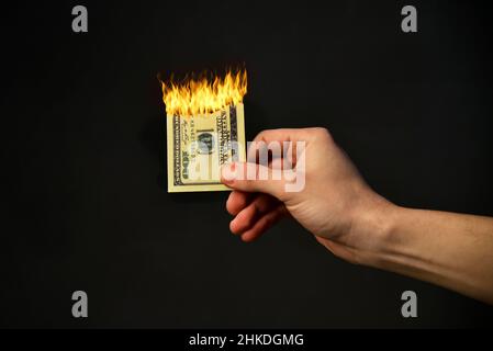 Bolletta in fiamme tenere in mano gli uomini contro uno sfondo nero. Foto Stock