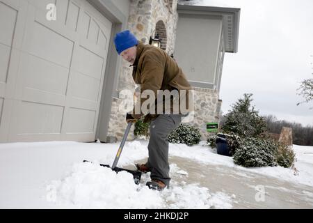 Flower Mound, Texas, USA. 3rd Feb 2022. Un uomo svela la neve dal vialetto dopo un freddo fronte colpito North Texas, portando pioggia gelida e neve nella regione. Nel 2021, il Texas ha vissuto una delle peggiori tempeste invernali della storia che ha portato alla chiusura della rete elettrica dello stato per migliaia di residenti. (Credit Image: © Chris Rusanowsky/ZUMA Press Wire) Foto Stock