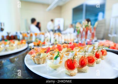 Catering in ufficio. Un tavolo con tartine e vari spuntini serviti sullo sfondo di un incontro d'affari Foto Stock