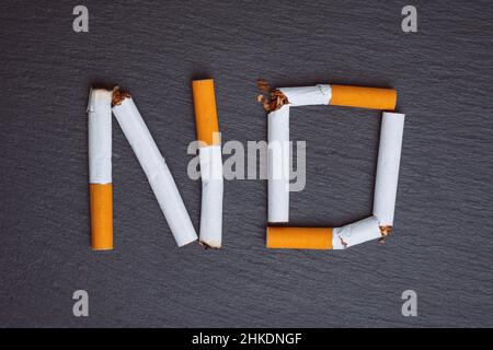 Non fumare parola fatta da sigarette rotte su uno sfondo nero Foto Stock