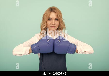 donna in cuoco grembiule che tiene pugni in guanti da boxe, potere Foto Stock