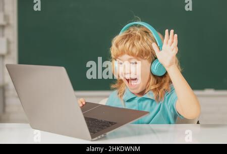 Emozioni stupite per i bambini. Bambino ragazzo in cuffie utilizzando un portatile e studiare online con un insegnante di videochiamata a scuola. Foto Stock