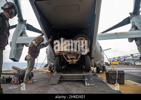 MAR DELLE FILIPPINE (Feb 3, 2022) i Marines statunitensi assegnati a Marine Medium Tiltrotor Squadron (VMM) 165 (rinforzato), 11th Marine Expeditionary Unit (MEU), caricano un veicolo polaris MrZR Light Tactical All-Terrain su un MV-22B Osprey collegato a VMM-165 (Rein.), 11th MEU, sul ponte di volo della nave d'assalto anfibio Wasp-class USS Essex 2 (LHD Essex) A sostegno di Exercise Noble Fusion, 3 febbraio 2022. In quanto unità preinstallata in grado di condurre operazioni anfibie, di rispondere alle crisi e di effettuare limitate operazioni di emergenza, il MEU 11th svolge regolarmente una formazione per poter operare nelle aree contestate t Foto Stock