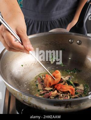 Mettere Kimchi con Chopstick alla padella, processo di cottura che rende cibo coreano Kimchi Bokkeumbap, fuoco selettivo Foto Stock