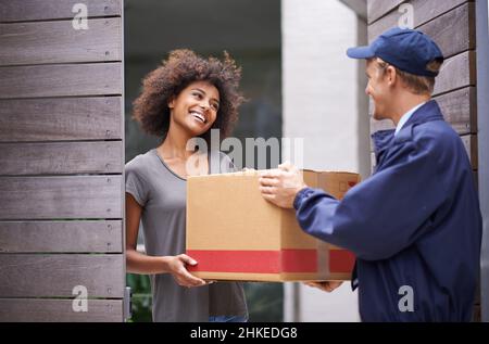 Consegna diretta a casa tua. Shot di un corriere che effettua una consegna a un cliente sorridente. Foto Stock