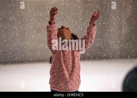 Prattville, Alabama, USA- 23 dicembre 2021: La giovane ragazza guarda in meraviglia alla neve artificiale che galleggia sulla pista di pattinaggio su ghiaccio in do storico Foto Stock