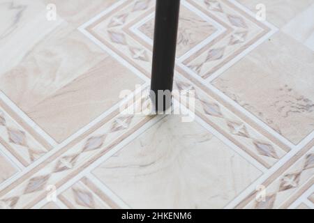 Linoleum strappato. Gamba sedia e linoleum lacerato. Foro nel linoleum. Sedia sul pavimento. Tracce di utilizzo di rivestimenti per pavimenti. Resistenza all'usura. Protezione agai Foto Stock