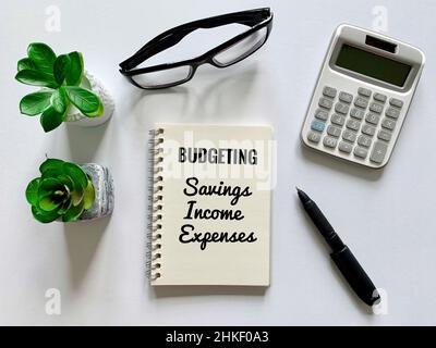 Testo di bilancio su blocco note con carta bianca, occhiali, calcolatrice e sfondo penna. Concetto di revisione finanziaria. Foto Stock