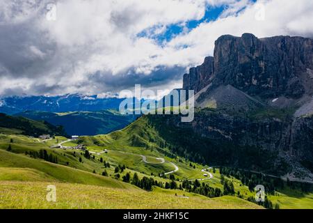 Una strada tortuosa che conduce al Passo Gardena, a destra si affacciano le pareti rocciose del gruppo Sella. Foto Stock