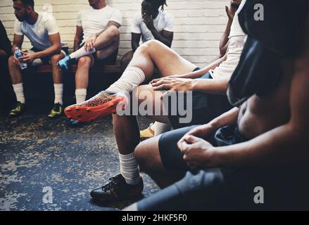 Il gioco più grande è oggi. Un'inquadratura di un gruppo di giocatori di rugby irriconoscibili seduti in un armadietto durante il giorno. Foto Stock