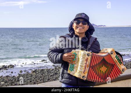 Un giovane a metà degli anni '20 in posa con la sua fisarmonica sul malecon; Puerto Penasco, Baja California, Messico. Foto Stock