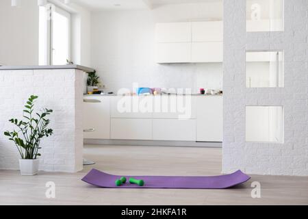 Formazione a casa concetto, interno, sport decorativo in camera con palestra fitness esercizio viola mat, dumbbell Foto Stock