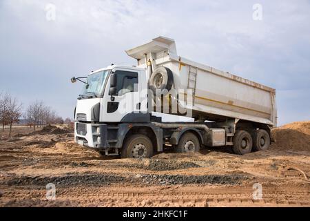 il dumper da cantiere esegue lavori di scavo in cantiere. Scarico del terreno. Lavori preparatori di terra prima della costruzione Foto Stock