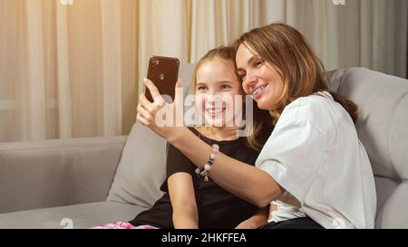 Madre e figlia teen fanno selfie in soggiorno a casa Foto Stock