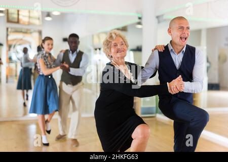 Donna matura imparando a ballare lindy hop con l'uomo più giovane Foto Stock
