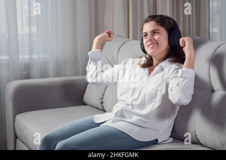 La donna con cuffia per disabili ascolta musica danzante sul divano Foto Stock