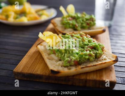 fette tostate di pane quadrato con formaggio caldo e guacamole fatte in casa sul piatto per una colazione sana Foto Stock