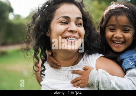 Felice madre indiana che si diverte con sua figlia all'aperto - fuoco morbido sulla faccia della mamma Foto Stock